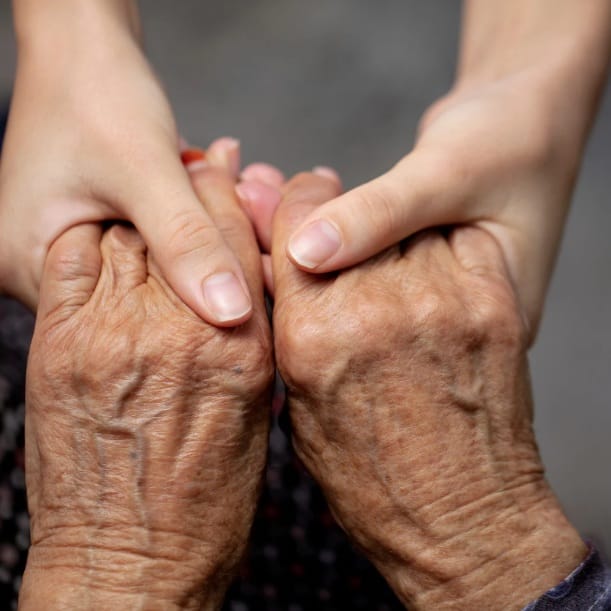 Cuidadora segurando as mãos de uma idosa em atendimento domiciliar em Jacareí